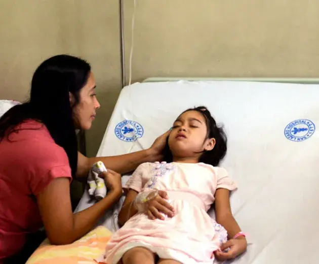 Girl in hospital bed being cared for